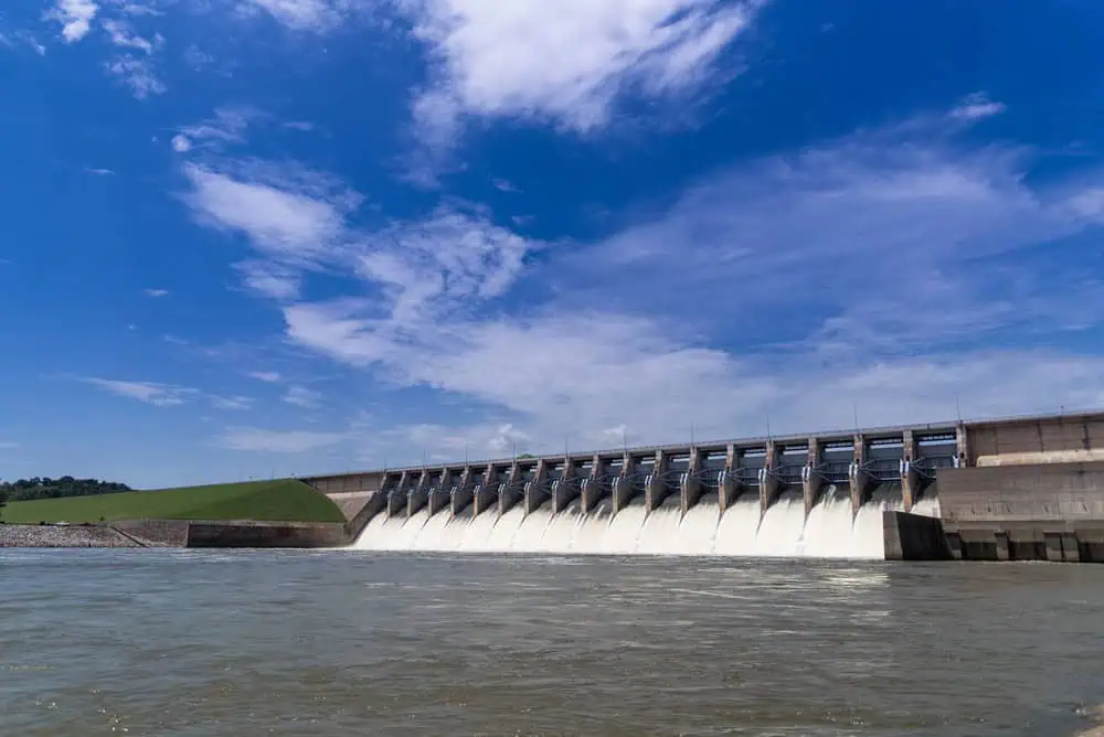 Hydroelectric dam releasing water under blue sky.